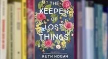 The book "The Keeper of Lost Things" by Ruth Hogan, library shelf in background